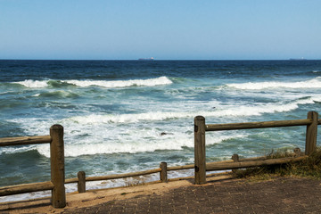 Wood Pole Barrier Sea Waves and Blue Skyline Background