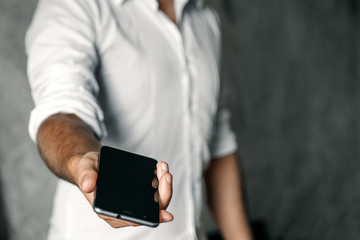 Close-up, the hand of a man with a phone on the background of concrete. Businessman.
