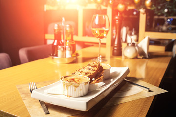 Julien in a white kokotnitsa and ciabatta on a table in a restaurant. Table setting at the restaurant.