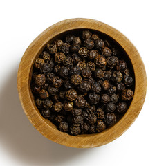Whole black pepper in dark wood bowl isolated on white from above.
