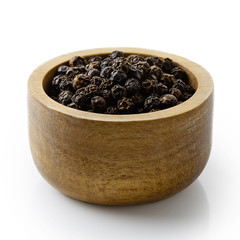 Whole black peppercorns in dark wood bowl isolated on white.