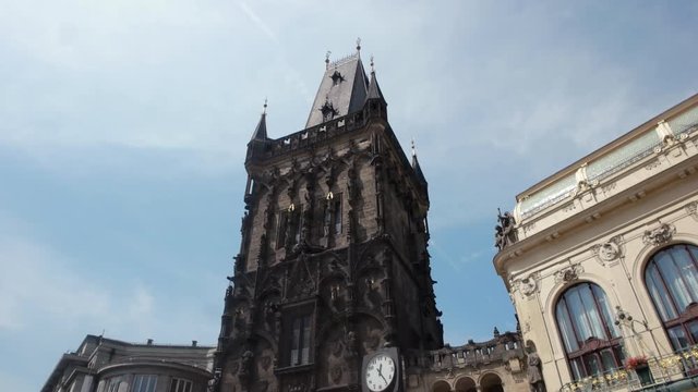 A walking shot down a old town Prague street looking up at the building facades and old cityscape, ancient huge tower, old multistoreyed building with an arc