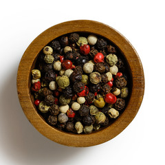 Mixed peppercorns in dark wood bowl isolated on white from above.