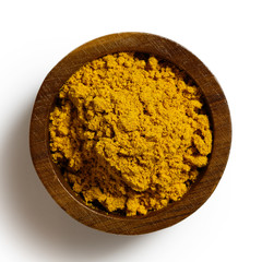Curry powder in dark wood bowl isolated on white from above.