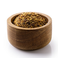 Dry ground brown mustard seeds in dark wood bowl isolated on white.