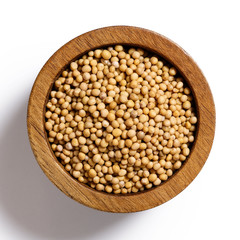 Dry white mustard seeds in dark wood bowl isolated on white from above.