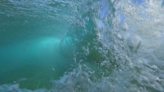 UNDERWATER SLOW MOTION: Barrel wave forming near the shore breaking into foam and countless air bubbles. Beautiful Oceanside scenery at Lobos island. Crystal clear water revealing the ocean floor.