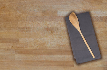 Kochlöffel und Küchentuch auf gebrauchtem Holzbrett