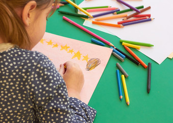 The child draws at the table in the kindergarten.
