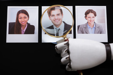 Robot Looking At Candidate Photograph With Magnifying Glass