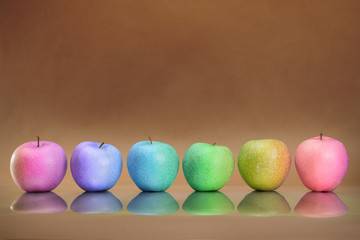 Six rainbow colored apples in the row