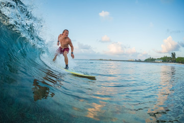 Surfer rides the wave during sunrise surf session. Maldives