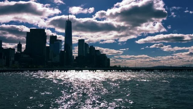Dramatic scenic timelapse of winter clouds moving across a silhouette of the New York City skyline with sun sparkling on the Hudson River