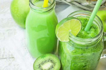 Glass Mason Jar and Bottle with Green Vegetable and Fruit Smoothie and Juice with Straw. Basket with Seasonal Organic Produce in Background. Spring Summer Detox Healthy Diet.