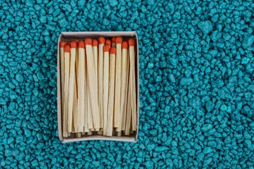 открытый коробок с спичками на мелких синих камнях