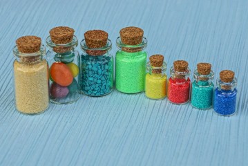 набор цветных стеклянных флаконов с песком на синем...