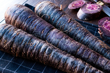 Purple Carrots on Dark Wooden Surface.