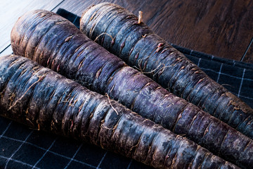 Purple Carrots on Dark Wooden Surface.