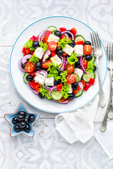 Greek salad of fresh cucumber, tomato, sweet pepper, lettuce, red onion, feta cheese and olives with olive oil. Healthy vegetarian food