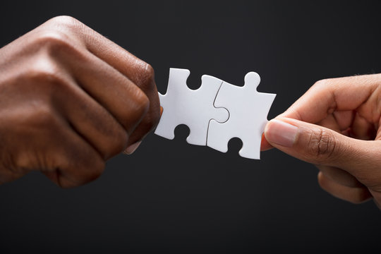 Hands Combining White Puzzle Pieces