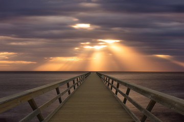 Fototapeta na wymiar A wooden footbridge that goes into the sea
