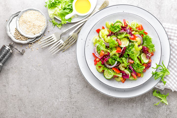 Salad of fresh cucumber, celery, sweet pepper, frize lettuce, red onion and sesame seeds with olive oil. Healthy vegetarian, vegan food. Italian cuisine