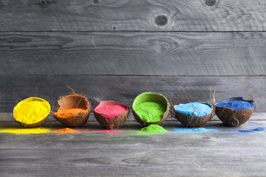Festival of colors. Bright colors for holi festival. Colorful holi paint in coconut shells on a wooden table with copy space. Creative shoot.