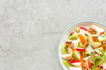 Fruit salad of fresh sweet apple, pear, tangerine and walnuts. Healthy vegetarian food