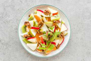 Fruit salad of fresh sweet apple, pear, tangerine and walnuts. Healthy vegetarian food