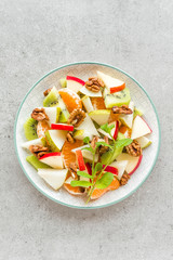 Fruit salad of fresh sweet apple, pear, tangerine and walnuts. Healthy vegetarian food