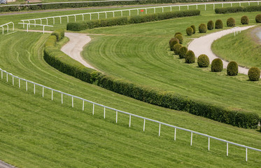 A view from the stand on an empty racing track. Treated green grass ready for horse racing.