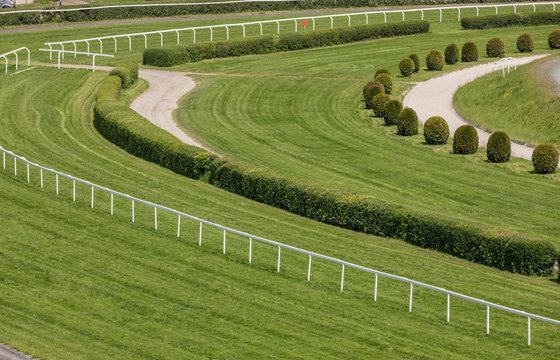 A view from the stand on an empty racing track. Treated green grass ready for horse racing.