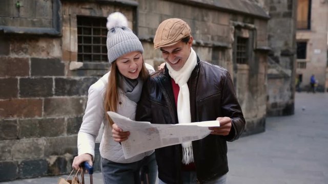 Smiling couple man and woman in the historic center with map in autumn