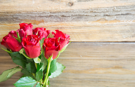 Bunch of red roses on wooden background.