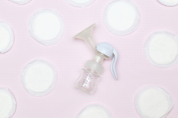 Manual breast pump with breast pads on the pink background