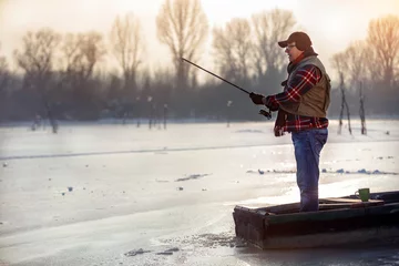 Selbstklebende Fototapeten elderly man fishing in the winter © luckybusiness