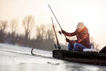 Poster ice fishing on frozen lake- fisherman catch fish © luckybusiness