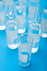 An open and empty ampoule with medicine on a background of blurred ampoules.