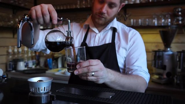 Close up barista in coffee shop pouring Syphon coffee into glass