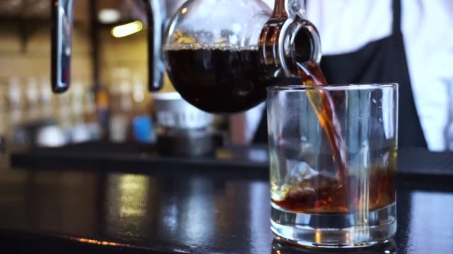 Close up barista pouring Syphon coffee into glass in coffee shop