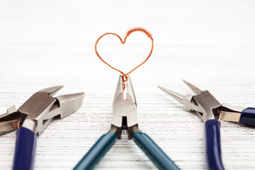 Jewelry tools on white background. Heart made of copper wire. Wire wrap