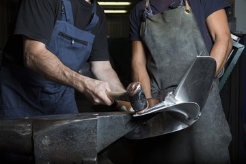 two man work with anvil and hammer on boat propeller
