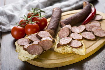 Sandwiches with homemade smoked sausage located on a board - food for consolation - tasty and healthy