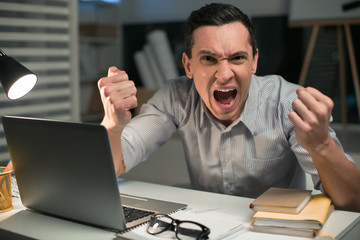 Emotional freedom. Stressful good looking male employee holding fists while crying and looking at...