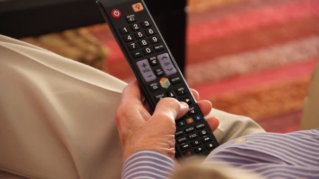 Elderly man using tv remote control 