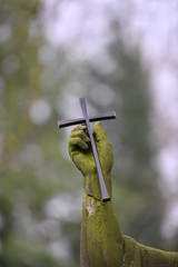 Christian cross in the weathered hand of a tomb sculptre