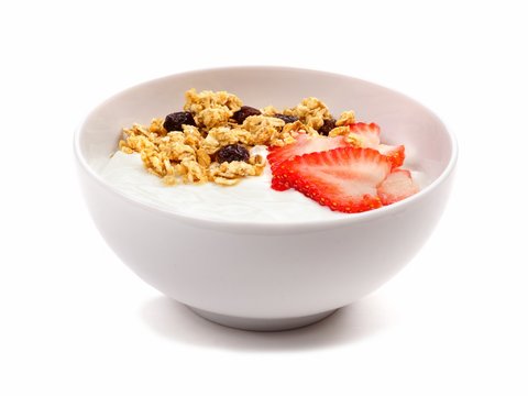 Yogurt with strawberries and granola in a white bowl. Side view, isolated on a white background.