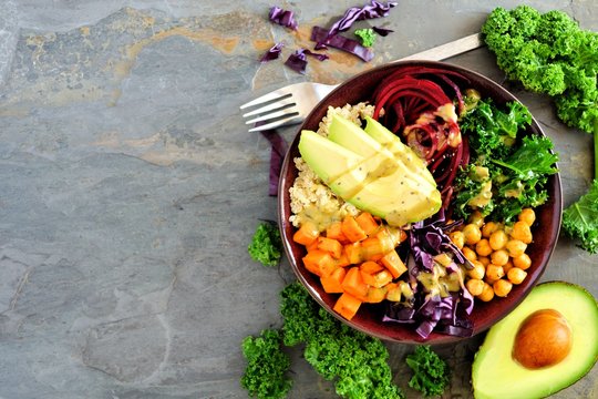 Buddha bowl with quinoa, avocado, chickpeas, vegetables on a dark background, Healthy food concept. Top view, side border with copy space.