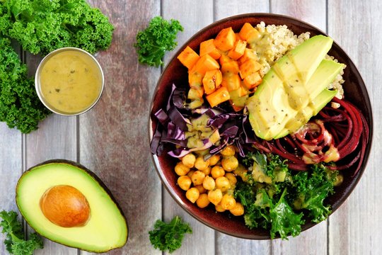 Buddha bowl with quinoa, avocado, chickpeas, vegetables on a wood background, Healthy eating concept. Overhead scene.