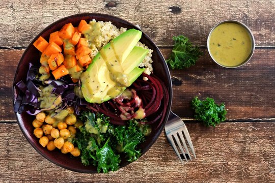 Buddha bowl with quinoa, avocado, chickpeas, vegetables on a wood background, Healthy food concept. Top view.
